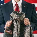 Man in suit holding military uniform American flag