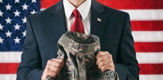 Man in suit holding military uniform American flag