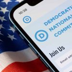 Schumer’s Surprising Endorsement: What It Means for DNC’s Future Leadership Smartphone screen showing Democratic National Committee website above flag.