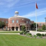 Large brick school building with flags and trees