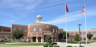Large brick school building with flags and trees