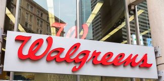 Walgreens store entrance sign with city reflections.