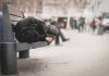 Person sleeping on a bench in a public area.