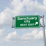 Tom Homan Sparks Debate: Sanctuary Cities and Public Safety at Odds? Green sign saying "Sanctuary City Next Exit."