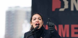 Person speaking passionately at outdoor event podium