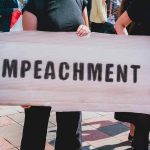 Ilhan Omar’s Impeachment Drive: Genuine Push or Political Strategy? Person holding an Impeachment sign at protest.