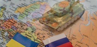 Ukraine and Russia flags with toy tank on map