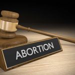 Louisiana Abortion Case Sparks Debate Over State Policy Conflicts Gavel and sign reading "Abortion" on a wooden surface.