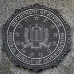 FBI seal on granite wall displaying department motto