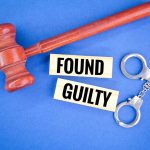 Gavel handcuffs and text found guilty on blue