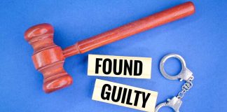 Gavel handcuffs and text found guilty on blue