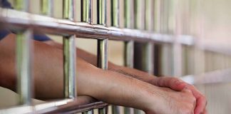 Hands resting on prison bars