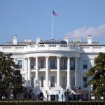 How Trump’s Tariff Plan Reshapes the Economy and Job Market White House with American flag flying, daytime.
