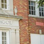 Brick school building with windows and foliage.