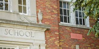 Brick school building with windows and foliage.
