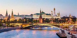 Illuminated bridge and Kremlin complex across river at twilight