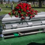 Silver casket with rose bouquet in a cemetery