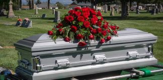 Silver casket with rose bouquet in a cemetery