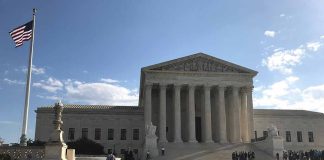Supreme Court building with flag and people outside