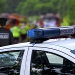 Decorated Officer’s Downfall Raises Questions on Community Trust Police car and officer at a scene.