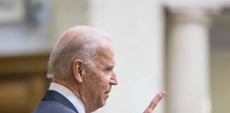 Man in suit pointing while speaking at podium