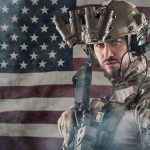 ICE Operations in Sanctuary Cities: Necessary or Overreach? Soldier in gear standing in front of American flag