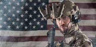 Soldier in gear standing in front of American flag