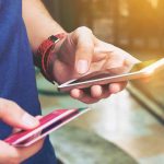 Banking on Trouble: How Hackers Exploit Outdated Smartphones Person holding smartphone and credit card outside