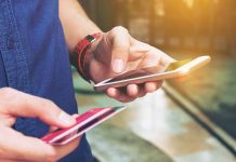 Person holding smartphone and credit card outside