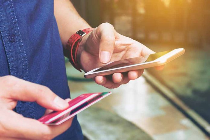 Person holding smartphone and credit card outside