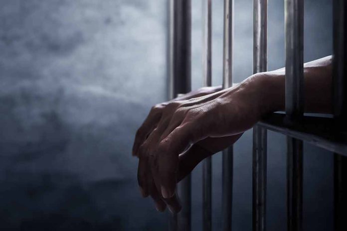 Hands gripping prison cell bars.