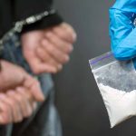 Handcuffed person with small bag of white powder