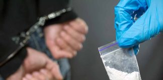 Handcuffed person with small bag of white powder