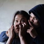 Man holding woman mouth gesturing silence