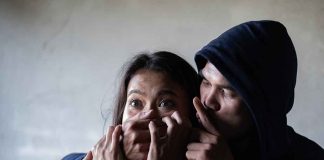 Man holding woman mouth gesturing silence