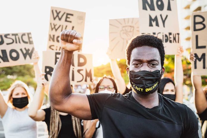 1762143443 featured image Protester raises fist wears mask signs in background