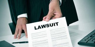 Person holding a document titled LAWSUIT in office