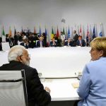 People seated around a large round table flags behind