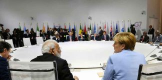 People seated around a large round table flags behind