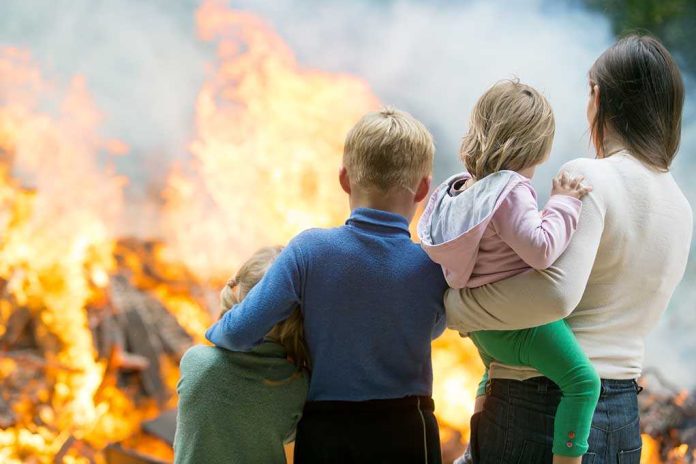 220431301. featured image Three children and adult watching large fire outdoors