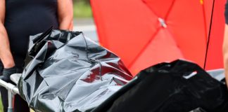 Person carrying body bag on stretcher outdoors