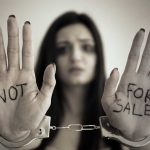 Handcuffed woman shows NOT FOR SALE on her palms