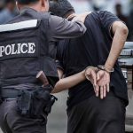 Police officer arrests handcuffed person