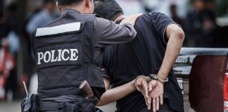 Police officer arrests handcuffed person