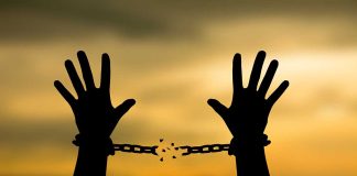 Hands breaking free from chains at sunset