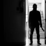 Silhouette of person with knife in dimly lit hallway
