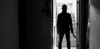 Silhouette of person with knife in dimly lit hallway
