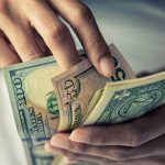 Person holding multiple US dollar bills