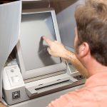 Person using touchscreen voting machine in polling booth