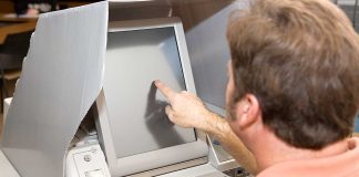 Person using touchscreen voting machine in polling booth